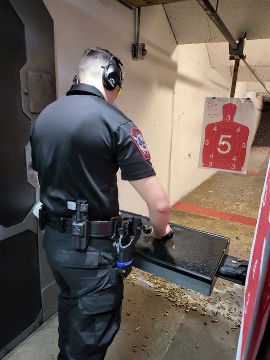 A police officer is standing in front of an ar target.