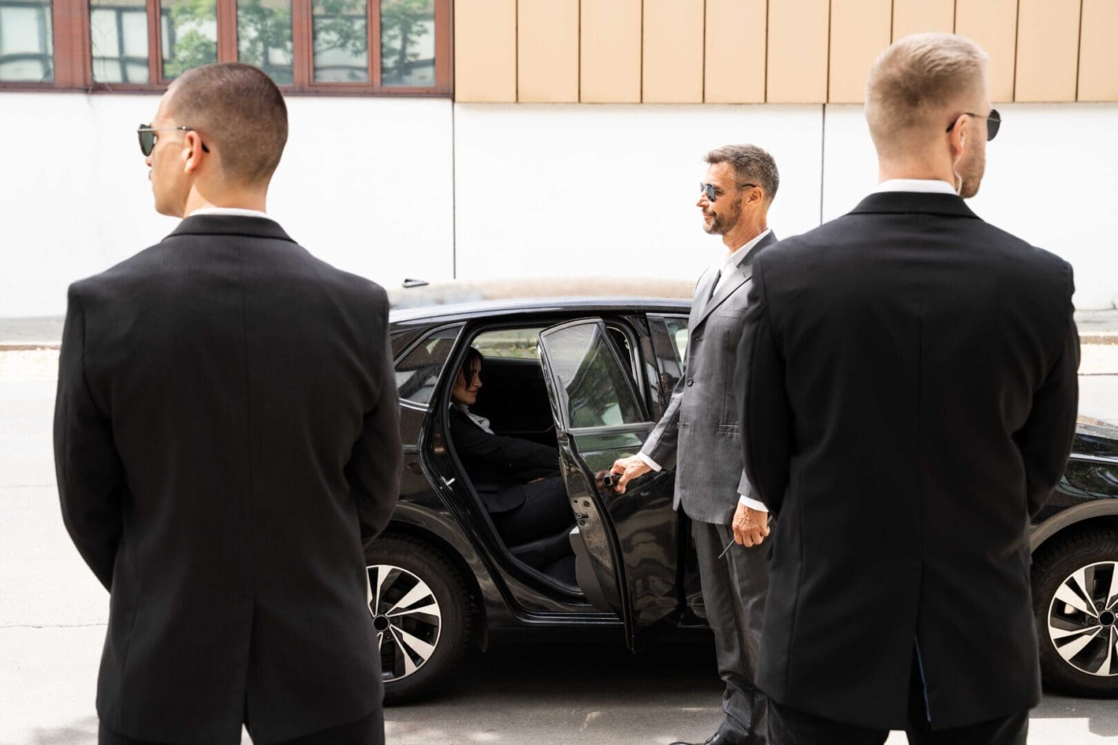 A man in a suit and tie standing next to an open car door.